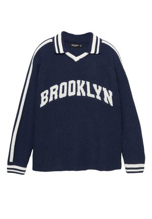 Tamno plavi pleteni pulover s bijelim prugama na rukavima, bijelim rubom ovratnika i natpisom "BROOKLYN" velikim bijelim slovima preko grudi.
