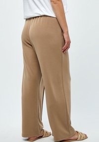 Beige wijde broek gemaakt van zachte stof, met een elastische tailleband. Het ontwerp heeft een gladde textuur en een ontspannen pasvorm.