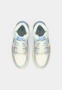 Para jasnoniebieskich i białych sneakersów Nike Air Jordan przedstawionych z góry na jednolitym białym tle.