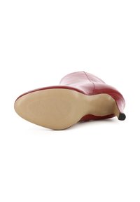 Rote Lederstiefel mit hohen Absätzen und spitzem Schuhleisten, glatter Oberfläche und einer leichten Gummisohle mit horizontalen Rillen für besseren Halt.