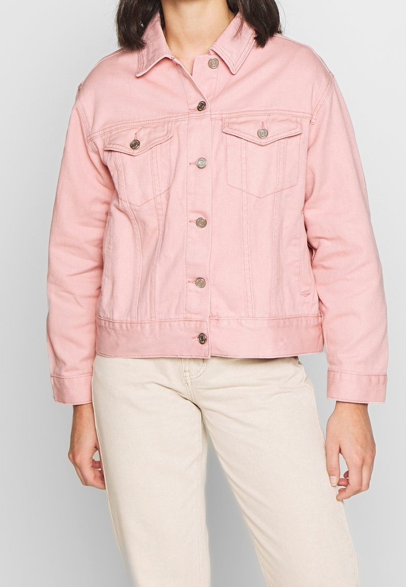 Rosa denimjacka med knäppning framtill, två bröstfickor och en något kortare hemline. Har kontrasterande silverknappar och en klassisk krage.