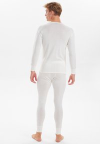 Weißes Langarm-Oberteil und passende Leggings aus weichem Stoff, mit gerippten Bündchen und tailliertem Design. Keine sichtbaren Muster oder Hardware.