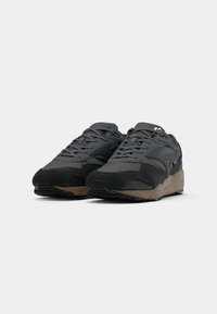 Black athletic shoes featuring synthetic upper with suede accents, round toe, lace-up front, and textured rubber sole in beige.