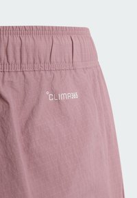 Gros plan sur un short à taille élastique mauve avec le logo blanc "Clima365" sur un tissu léger et texturé.