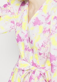 Abito a portafoglio bianco con motivo marmorizzato in rosa e giallo. Presenta una scollatura a V, maniche lunghe e un dettaglio di vita annodata.
