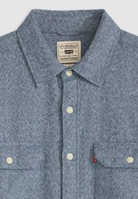 Blue speckled button-up shirt with a collar, two front pockets, and white buttons. Features a Levi's label at the neckline.