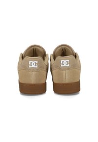 Béžové semišové tenisky s hnedou gumovou podrážkou, s bielym logom na päte a polstrovaným golierom pre pohodlie.