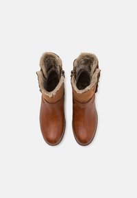 Braune Leder-Ankle-Boots mit einem weichen Kunstfellfutter, Schnallenakzenten und runder Zehenform. Glatte Textur mit kontrastierenden Materialien am Schaft.