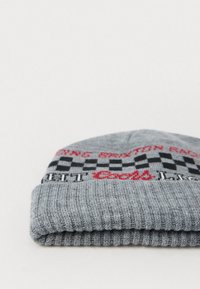 Gorro de punto gris con puño doblado. Presenta un patrón a cuadros en blanco y negro y texto bordado en rojo. Hecho de material suave y elástico.