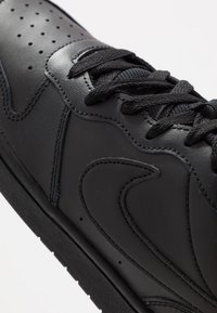 Must must sneakers, millemust nahk, sujuv välimus, perforeeritud varvas ja paks must kinnituspael. Kummi tald, millel on detailne õmblusaktsent.