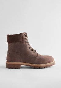 Bottine en cuir marron avec col en daim, bout rond, œillets en métal, lacets marron et semelle en caoutchouc robuste, présentant un design cousu.