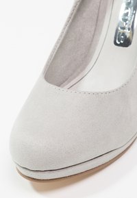 Chaussure à talon haut en daim gris avec un bout rond, une texture lisse et un détail de couture subtil le long du bord de l'ouverture.