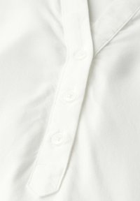 Camisa de algodón blanca con escote en V y cinco botones texturizados a lo largo del placket; tejido suave con un sutil brillo.