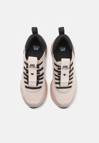 Heledad roosa sneakerid, millel on tekstureeritud kudumise pealmine osa, mustad paelad ja beež rihm, millel on logo ning kummist põhi koos aktsentvärviga.