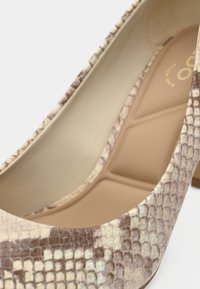 Chaussure à talon haut beige avec un motif texturé imprimé serpent. Doublure intérieure lisse et conception à bout pointu. Semelle de couleur claire.