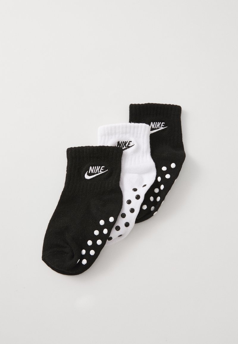 Três pares de meias de tornozelo: um par preto com bolinhas brancas, um par branco com bolinhas pretas, ambos com o logótipo da Nike na bainha. Material em mistura de algodão.