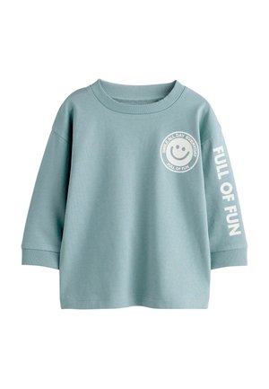 Türkisfarbenes Langarmshirt mit geripptem Rundhalsausschnitt und Bündchen, Smiley-Gesichtslogo mit „Smile all day everyday“ auf der Brust, Schriftzug „Full of fun“ am rechten Ärmel.