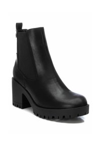 Botines negros de tobillo hechos de cuero suave, con paneles laterales elásticos, un tacón grueso y una suela resistente con surcos profundos.