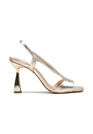 Złoty metaliczny sandał na wysokim obcasie typu slingback z kwadratowym otwartym noskiem i rozszerzanym, masywnym obcasem.