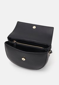 Borsa a spalla in pelle nera con forma arrotondata, hardware dorato e chiusura a scatto. L'interno presenta una tasca con zip e più scomparti.