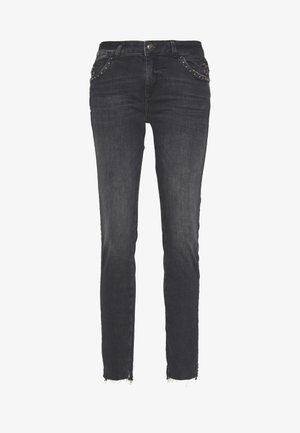 Czarne jeansy slim fit z ćwiekowanymi przednimi kieszeniami, zapinane na guzik i zamek błyskawiczny, z surowymi, postrzępionymi krawędziami przy kostkach.