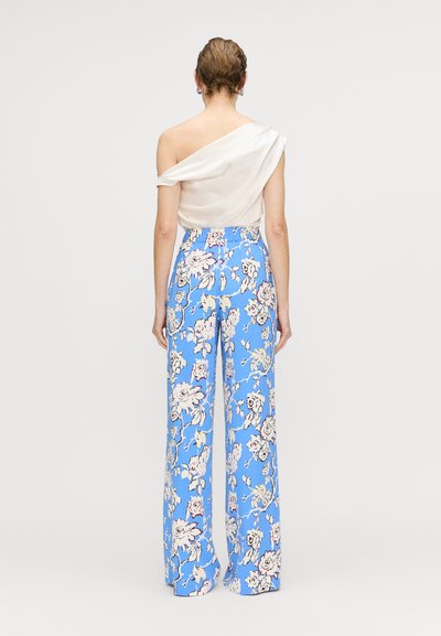 Hvid, off-the-shoulder top parret med blå blomster mønstrede brede bukser. Glat stof, let tekstur og stort, multikolor blomsterdesign.