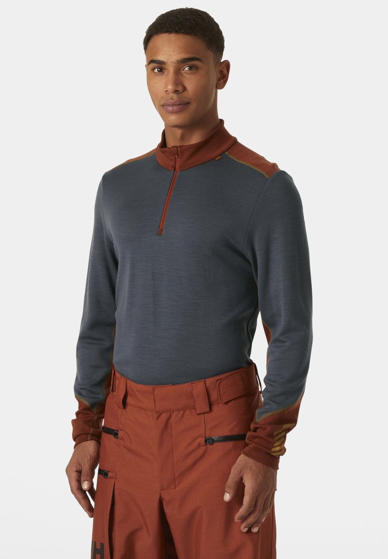 Donkerblauwe longsleeve pullover met een ritskraag, voorzien van kastanjebruine accenten op de schouders en manchetten, gemaakt van lichte stof.