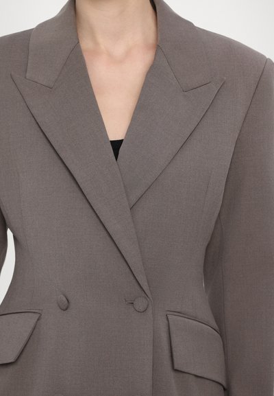Grau, doppelreihiger Blazer aus glattem Stoff mit großen Revers, Fronttaschen und Knopfakzenten auf der Brust und dem Verschluss.