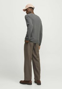 Gray long-sleeve shirt, loose-fitting brown pants, and light pink cap. Includes textured fabric and a rounded neckline. Brown shoes complete the outfit.