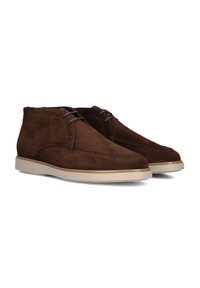 Bottines en suede marron avec une texture lisse, semelle en caoutchouc blanc et lacets ton sur ton. Présente des détails cousus le long du bord supérieur.
