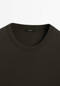 Mørkegrøn kortærmet t-shirt med rund halsudskæring og glat tekstur, med en subtil syningsdetalje omkring kraven.