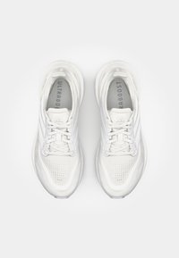 Hvite joggesko med overdel av pustende nettmateriale, teksturert såle og tre stripes detaljer. Har polstrede såler for komfort.