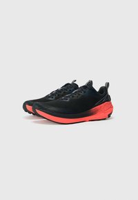 Chaussures de sport noires avec tige en tissu texturé, semelle intermédiaire rouge contrastante et semelle extérieure en caoutchouc noir. Présente un col rembourré et des lacets.