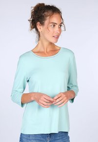 Helles Türkis langärmliges Hemd mit rundem Ausschnitt und zarter Borte. Der Stoff hat eine glatte Textur und eine lässige Passform.