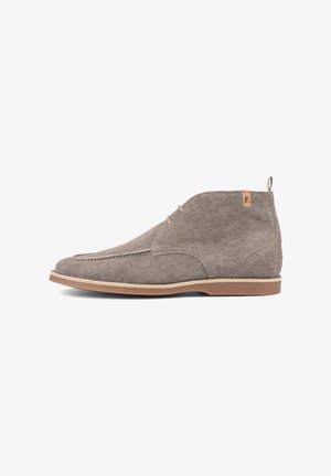 Beige suède heren enkellaars met zijveters, lichtbruine zool en kleine beige trekband met een "F"-logo op de hielkraag.
