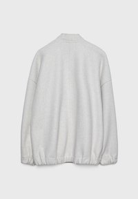 Lichtgrijze fleecjas met een ronde kraag, elastische onderrand en verlaagde schouders, met een soepele textuur en minimale naden op de achterkant.