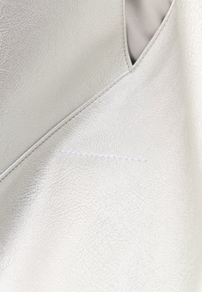 Κοντινή λήψη λείου ασημί δερμάτινου υφάσματος με λεπτομερείς ραφές κατά μήκος μιας διαγώνιας ραφής.