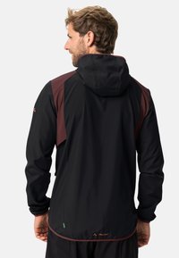 Schwarze und burgunderfarbene, leichte Jacke mit Kapuze, ausgestattet mit einer glatten Textur, verstellbaren Bündchen und einem Markenlogo am Saum.
