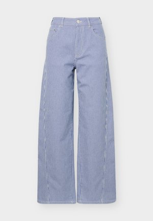 Sinised ja valged vertikaalselt triibulised laia jalaga püksid, millel on ees taskud ja vöö juures nööpkinnitus.