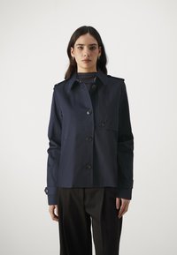 Marineblauwe waterdichte jas met een knoopsluiting aan de voorkant, schouderepauletten en een cropped ontwerp, met een soepele textuur en verstelbare manchet.