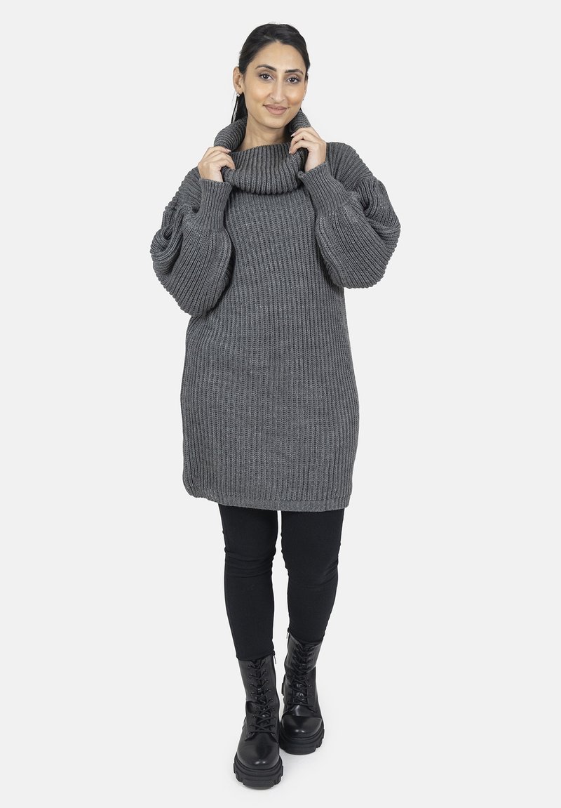 Grå ribbet sweaterkjole med høj cowl-hals og store ærmer, parret med sorte leggings og snørede combatstøvler.