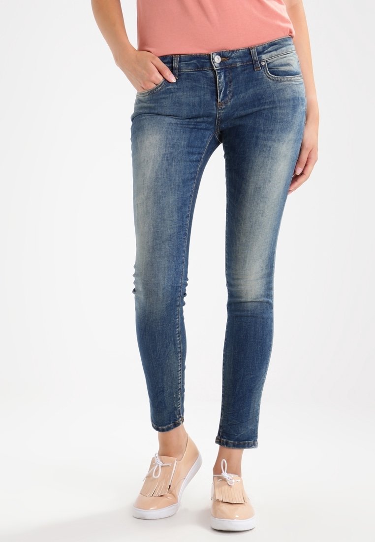 Blå denim skinny jeans med en bleknad tvätt, fem fickor och knappstängning. Matchas med ljusa platta skor.