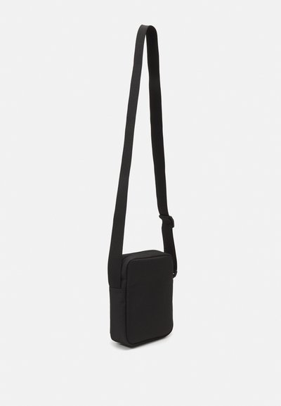 Sac à bandoulière noir en tissu avec une forme rectangulaire, un devant plat, une sangle ajustable et un design minimaliste. Texture lisse sans matériel visible.