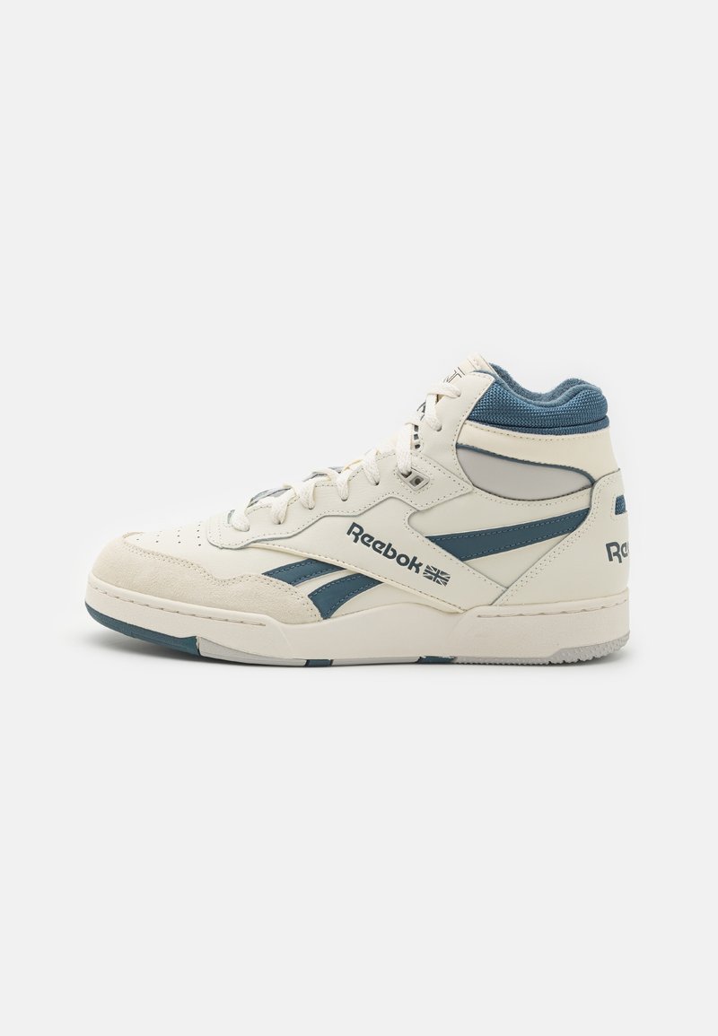 Basket montante Reebok en blanc crème avec des accents bleus, lacets, bout perforé et logos de marque sur le côté et le talon, présentée sur fond blanc uni.