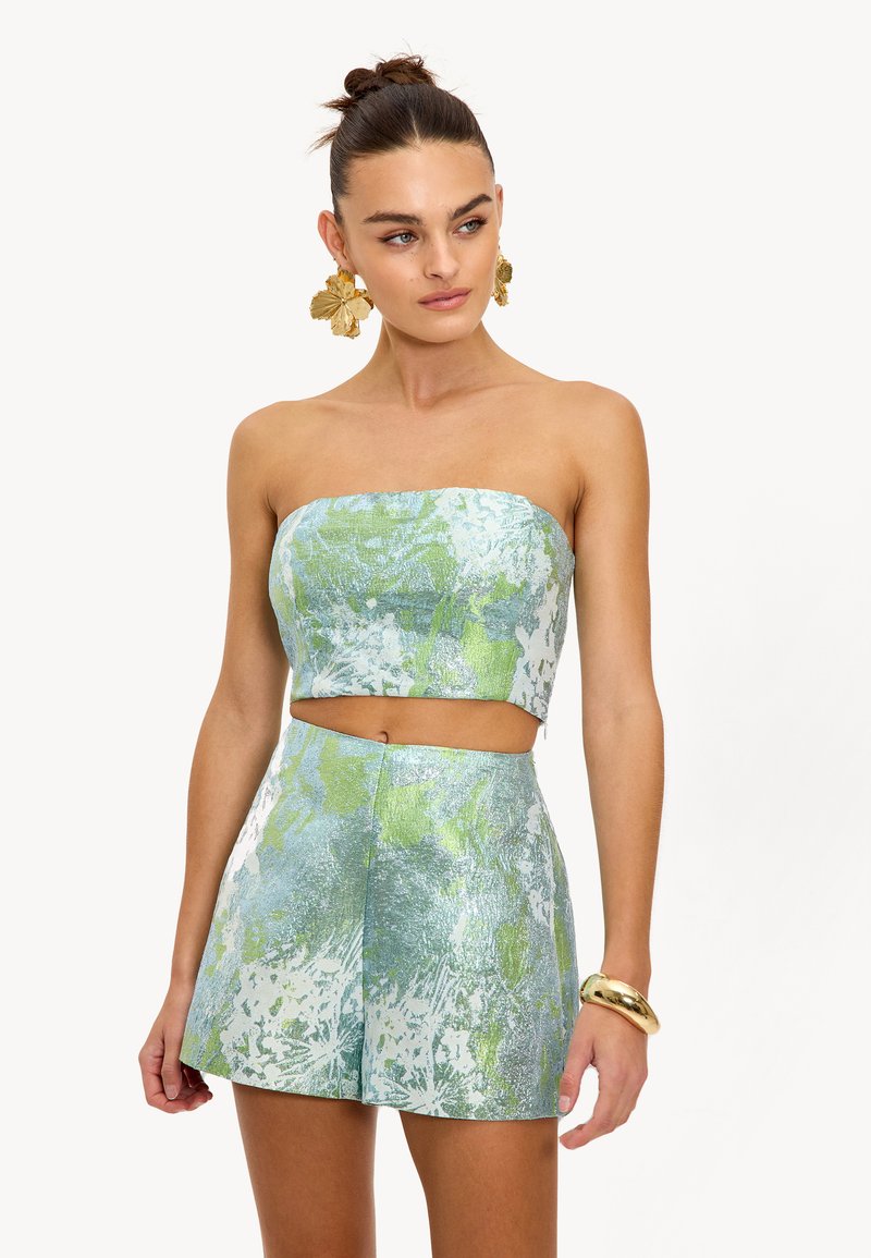 Twee-delige outfit met een strapless crop top en hoge taille shorts in een lichtblauw en groen abstract patroon met een glanzende afwerking.