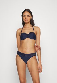 Marine bikini sett med polstret, halterneck topp som har en rynket kant og perlede detaljer. Bunnen har en matchende dekorativ midjebånd.
