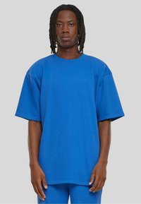 Blå, oversized T-skjorte, korte ermer, rund hals, laget av bomullsblandingsstoff. Glatt tekstur, ingen mønstre, sitter løst.