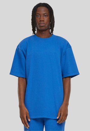 Tricou albastru de dimensiuni mari, cu mâneci scurte, guler rotund, realizat dintr-un amestec de bumbac. Textură netedă, fără modele, se potrivește lejer.
