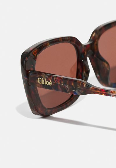 Ombre oversized con montatura in acetato tartarugato, lenti marroni e logo "Chloé" in oro sui bracci. Design angolare con finitura lucida.