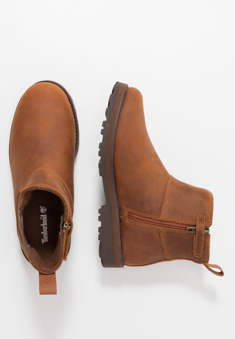 Botas de cuero marrón hasta el tobillo con un zipper lateral, superficie texturizada y suela de goma con surcos profundos para un mejor agarre. Lengüeta de talón reforzada.